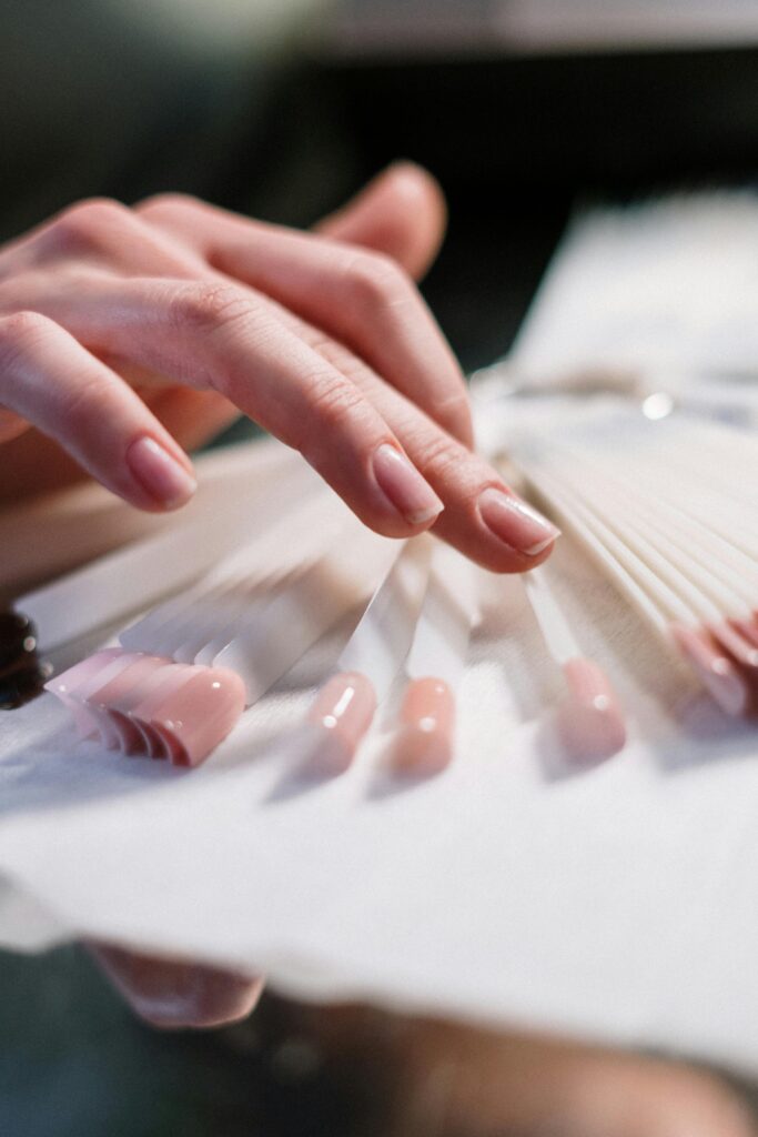 pexels-photo-3997379-3997379 Close-up of a woman's hand selecting nail polish colors in a beauty salon.